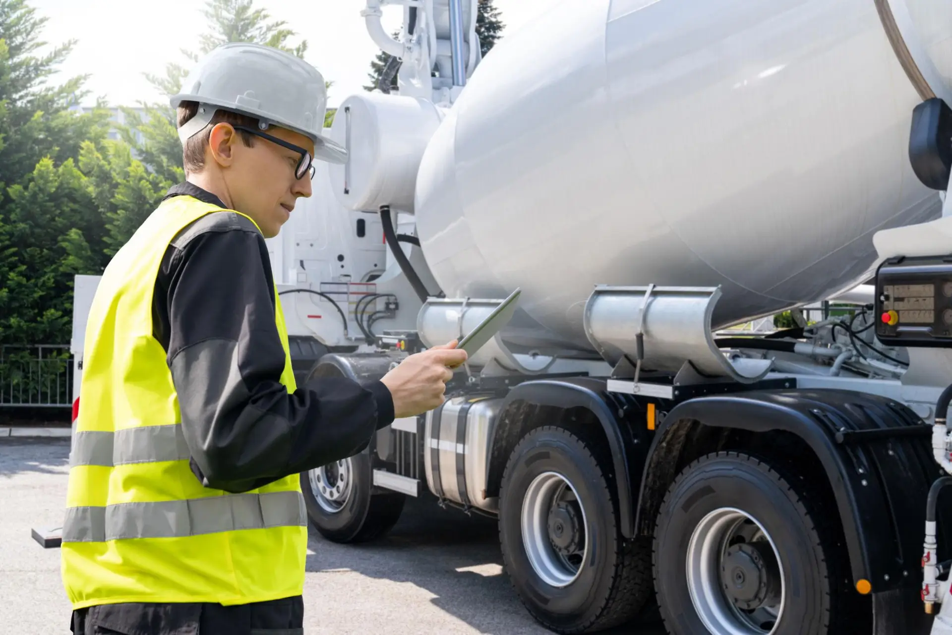 Construction worker looking at pad standing near a concrete truck